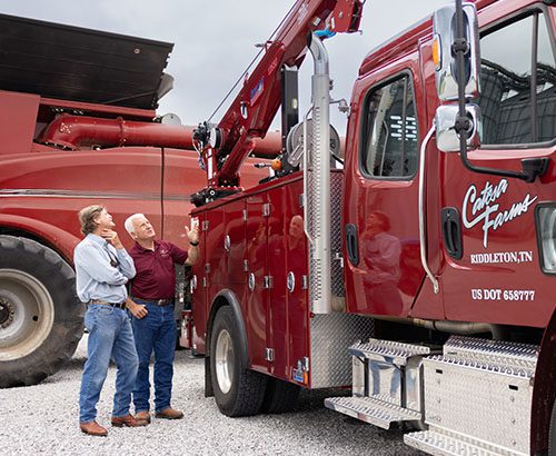 two men talking in front of red truck