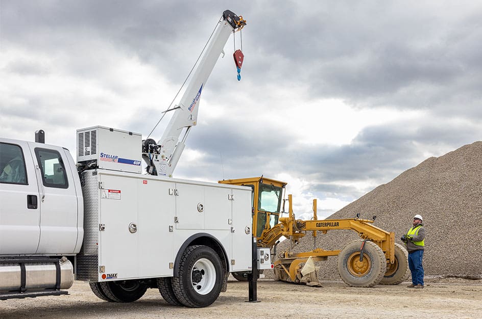 Worker in safety vest operating crane attached to a Stellar TMAX 2 mechanic truck.